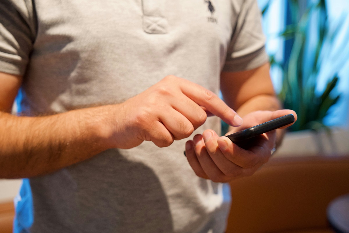 Un homme utilise son téléphone pour télécharger l'application mobile KDriver et discuter avec son chauffeur en ligne.